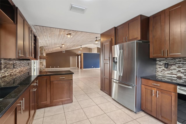 kitchen with light tile patterned floors, visible vents, vaulted ceiling, appliances with stainless steel finishes, and dark stone counters