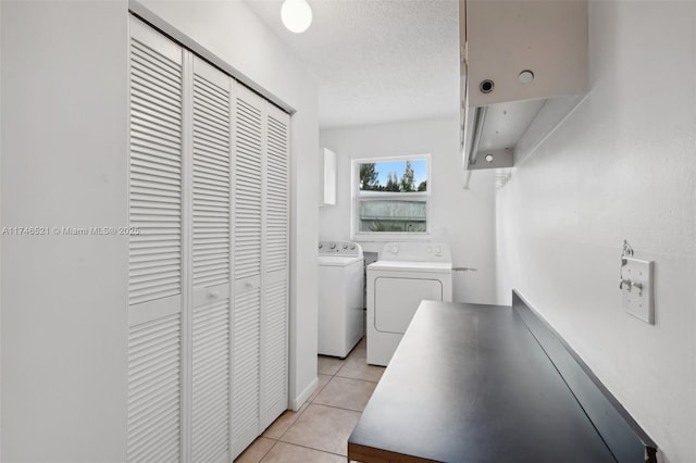 laundry room featuring laundry area, light tile patterned flooring, a textured ceiling, and washing machine and clothes dryer