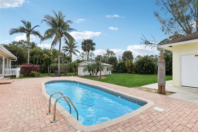 pool featuring a patio, a lawn, an outdoor structure, and fence