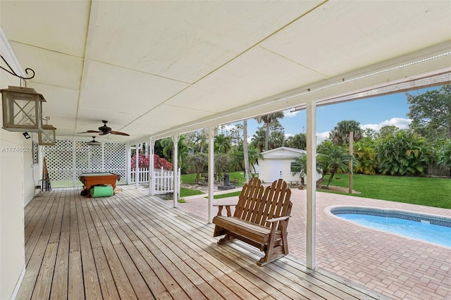 deck featuring a yard, ceiling fan, an outdoor pool, and an outdoor structure