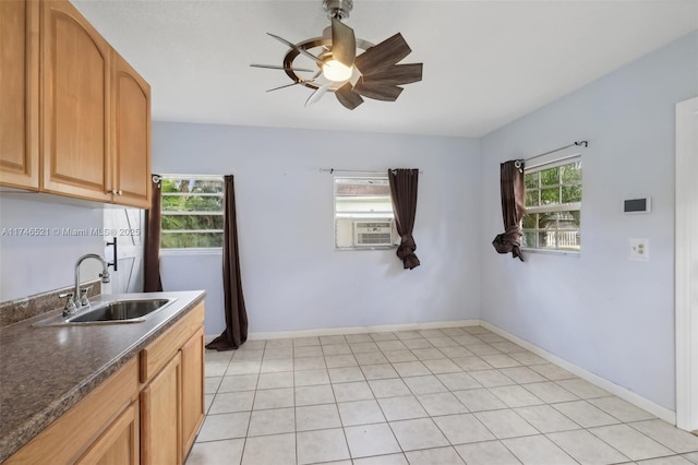 kitchen featuring dark countertops, baseboards, a ceiling fan, and a sink