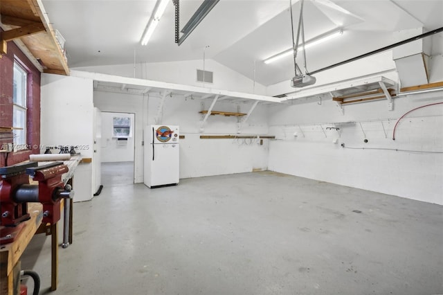 garage with visible vents, a garage door opener, and freestanding refrigerator