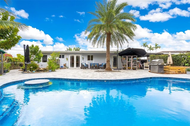 pool featuring french doors, a patio area, a grill, and an outdoor living space