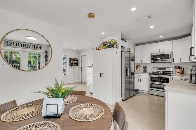 kitchen featuring light tile patterned floors, white cabinetry, light countertops, appliances with stainless steel finishes, and backsplash