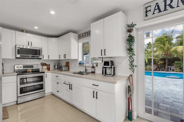 kitchen featuring backsplash, appliances with stainless steel finishes, light countertops, and a sink