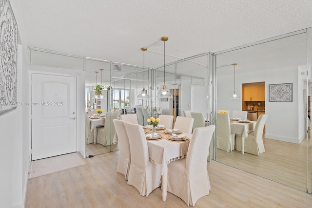 dining space with a textured ceiling, visible vents, and light wood-style flooring