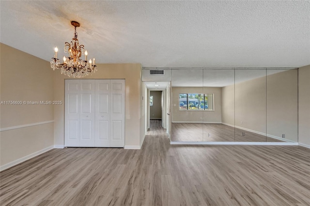 unfurnished bedroom with a closet, a textured ceiling, visible vents, and wood finished floors