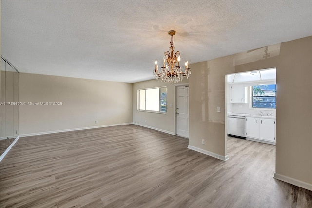 interior space with baseboards, a healthy amount of sunlight, a textured ceiling, and light wood finished floors