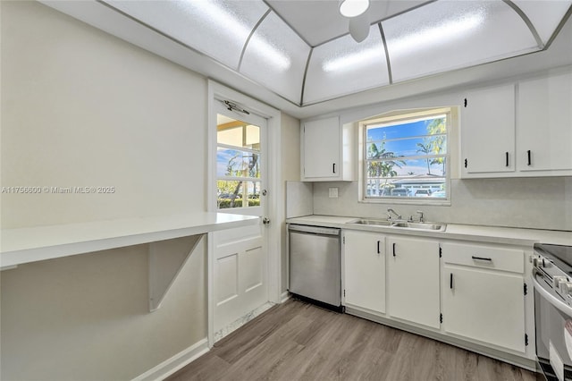 kitchen featuring a wealth of natural light, light countertops, light wood-style flooring, appliances with stainless steel finishes, and a sink