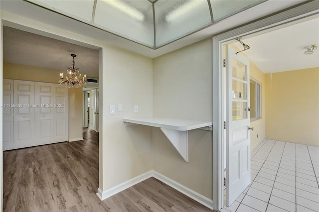 hall with an inviting chandelier, baseboards, and wood finished floors