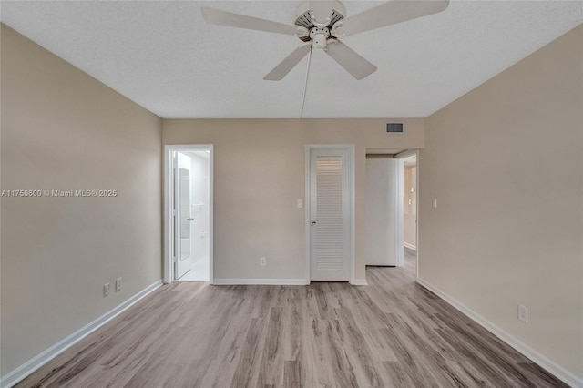 unfurnished bedroom featuring a textured ceiling, wood finished floors, visible vents, baseboards, and ensuite bath