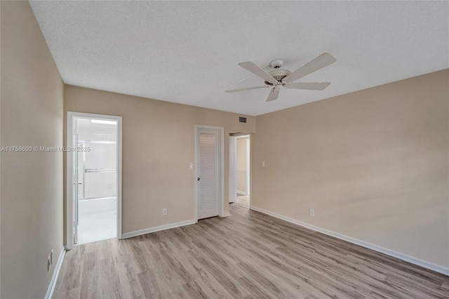 unfurnished bedroom with light wood finished floors, visible vents, baseboards, ensuite bathroom, and a textured ceiling