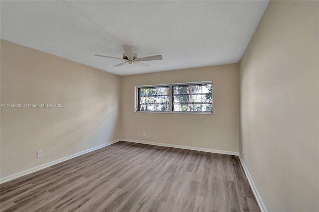 empty room with wood finished floors, a ceiling fan, and baseboards