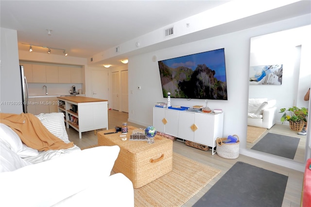 living room featuring baseboards, visible vents, and track lighting