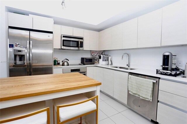 4250 Biscayne Blvd Unit 1512, Miami, FL 33137 - kitchen featuring stainless steel appliances, white cabinetry, light tile patterned floors, a kitchen breakfast bar, and modern cabinets