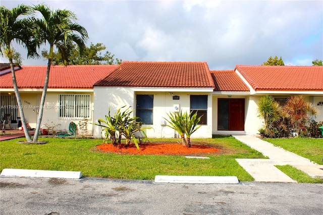 view of front of house featuring a tiled roof, a front lawn, and stucco siding