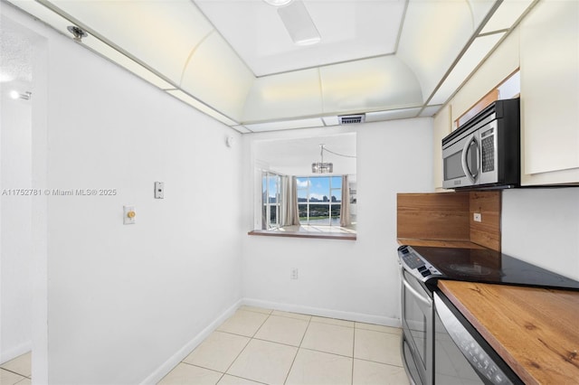 kitchen featuring light tile patterned floors, visible vents, baseboards, and stainless steel appliances