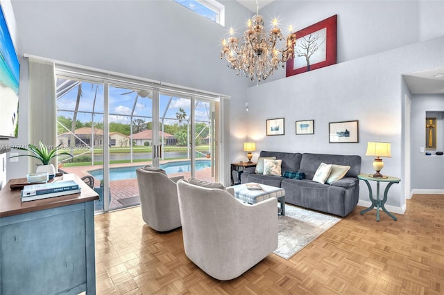 living area with a notable chandelier, a high ceiling, and baseboards