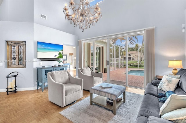 living area with a towering ceiling, visible vents, baseboards, and a chandelier