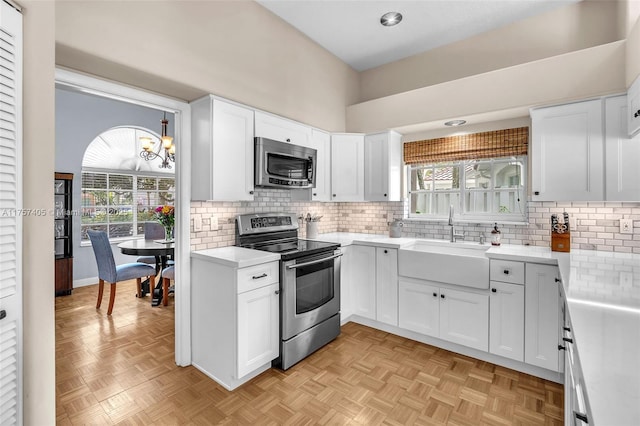 kitchen with light countertops, decorative backsplash, appliances with stainless steel finishes, white cabinets, and a sink