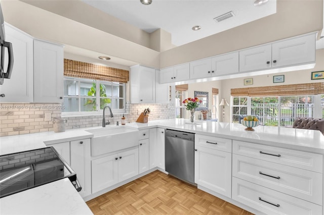 kitchen with white cabinets, dishwasher, a peninsula, light countertops, and a sink