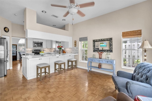 kitchen with a breakfast bar area, a peninsula, visible vents, open floor plan, and appliances with stainless steel finishes