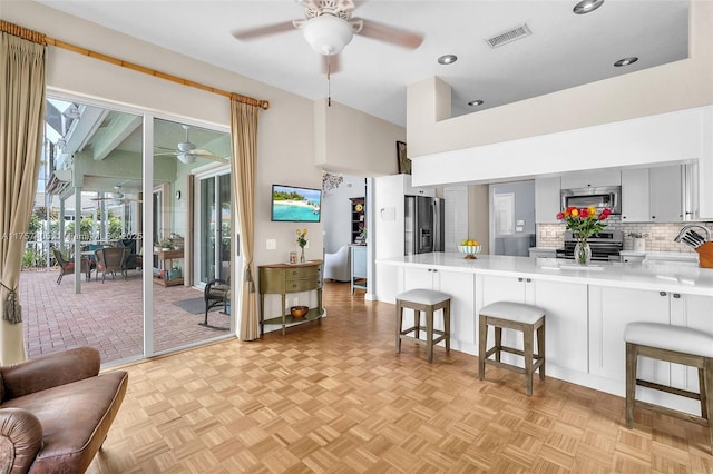 kitchen featuring appliances with stainless steel finishes, light countertops, a peninsula, and a kitchen bar