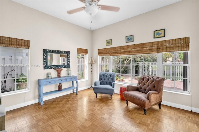 sitting room with ceiling fan, baseboards, and a wealth of natural light