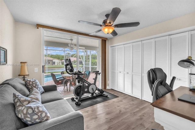 exercise room with a textured ceiling, ceiling fan, and wood finished floors