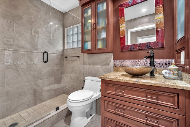 bathroom with decorative backsplash, toilet, vanity, a shower stall, and tile walls