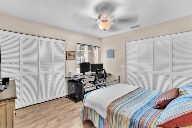 bedroom featuring a textured ceiling, light wood finished floors, visible vents, and a ceiling fan