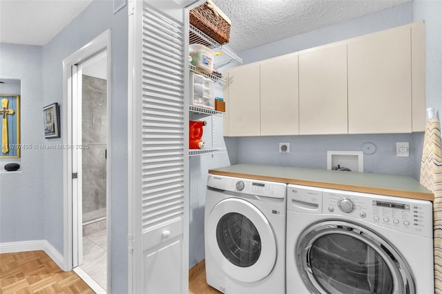 clothes washing area featuring a textured ceiling, independent washer and dryer, cabinet space, and baseboards