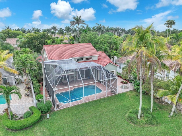 back of property featuring a lanai, an outdoor pool, a lawn, and a tiled roof