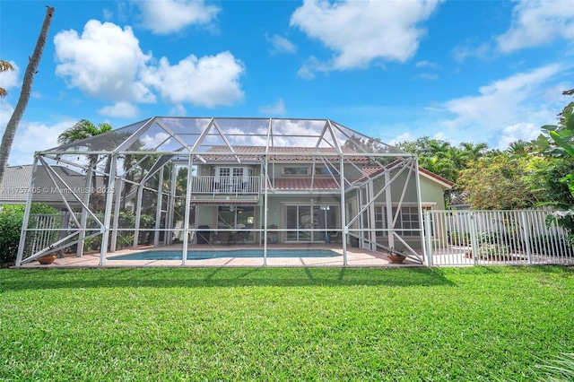 back of house featuring a lanai, fence, and a lawn