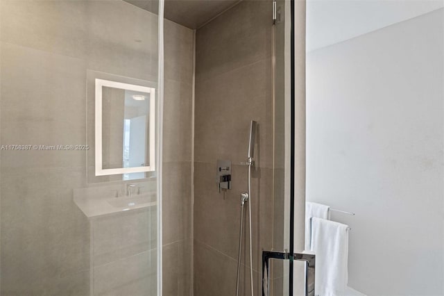 bathroom with tiled shower and a sink