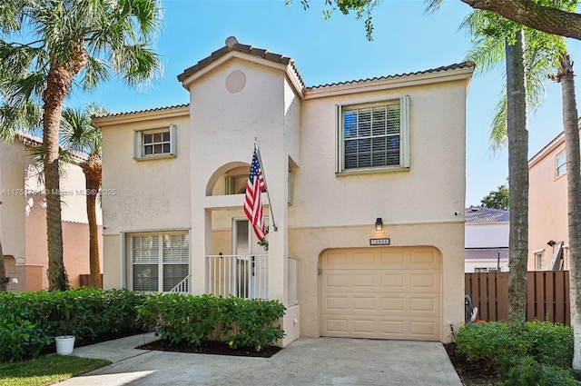 mediterranean / spanish-style house with a garage, fence, and stucco siding