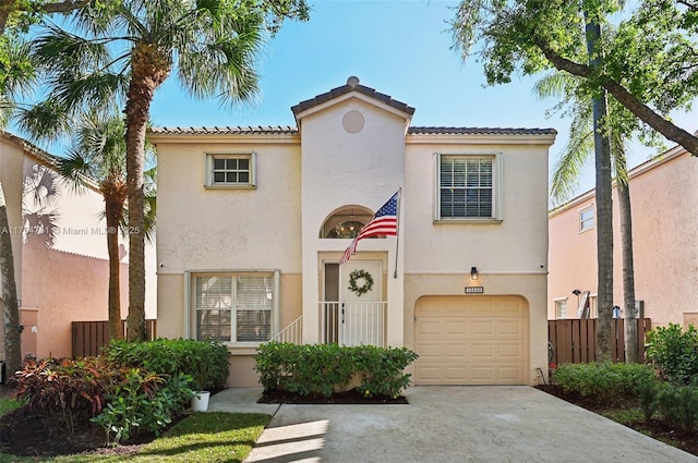 mediterranean / spanish-style house with fence, a garage, driveway, and stucco siding