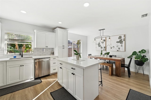 kitchen featuring visible vents, a sink, light wood-style floors, dishwasher, and tasteful backsplash