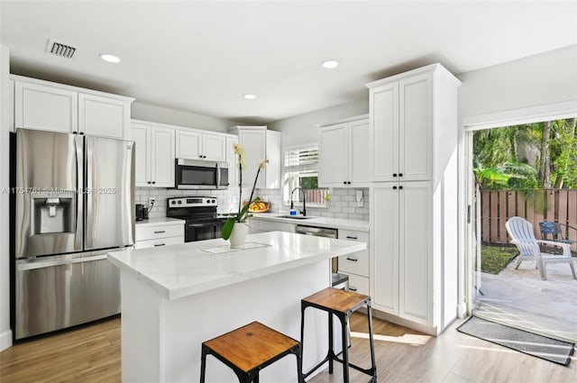 kitchen with white cabinetry, a center island, appliances with stainless steel finishes, and a sink