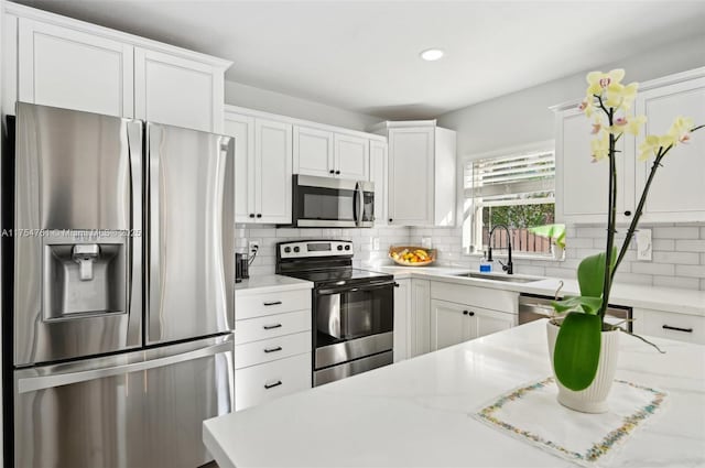 kitchen featuring a sink, stainless steel appliances, white cabinets, and light countertops