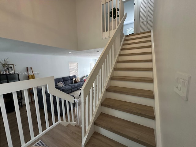 stairway with visible vents, a high ceiling, and wood finished floors