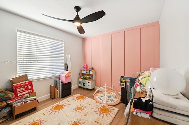 recreation room with a ceiling fan, wood finished floors, and baseboards