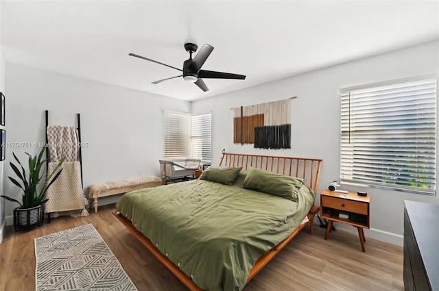 bedroom featuring baseboards, wood finished floors, and a ceiling fan