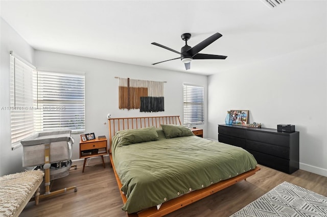 bedroom featuring visible vents, wood finished floors, baseboards, and ceiling fan