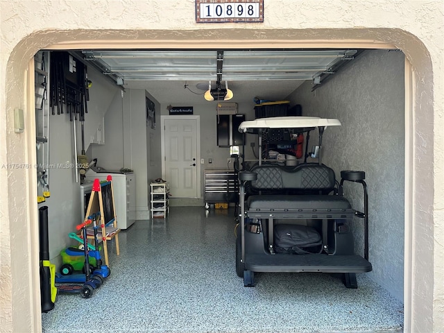 garage with separate washer and dryer, a garage door opener, and a textured wall