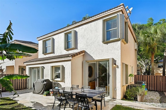 rear view of house with stucco siding, a patio, and fence