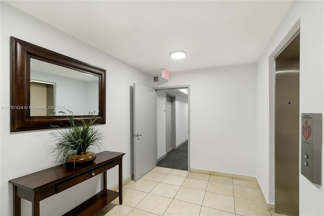 hallway with light tile patterned floors, baseboards, and visible vents