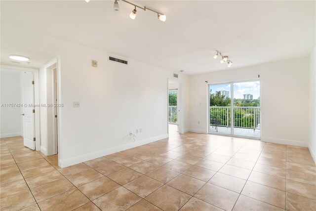 unfurnished room with baseboards, track lighting, visible vents, and light tile patterned floors