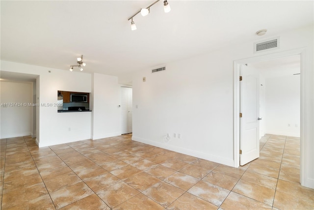 empty room with baseboards, visible vents, track lighting, and light tile patterned floors