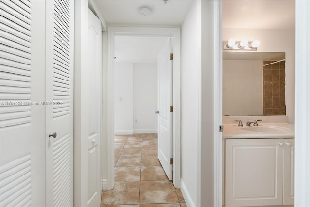 hallway featuring light tile patterned flooring, a sink, and baseboards